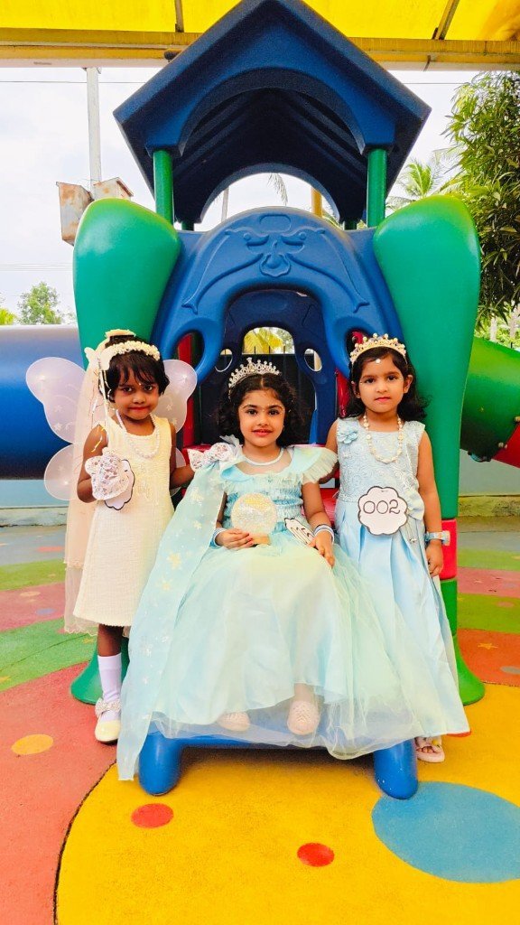 Three young girls in princess and fairy costumes posing at the Galaxy Infant School playground