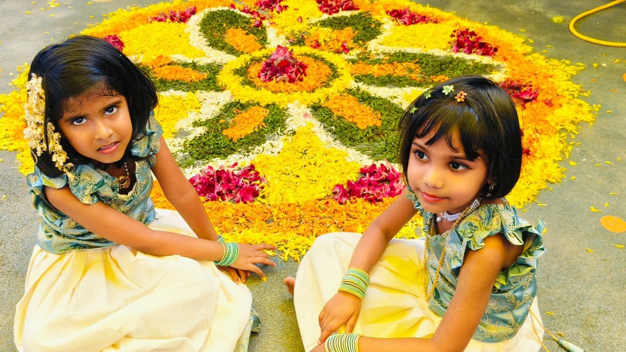 Girls arranging Onam pookalam floral designs