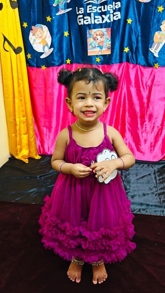 Toddler girl smiling on stage at La Escuela Galaxia celebration